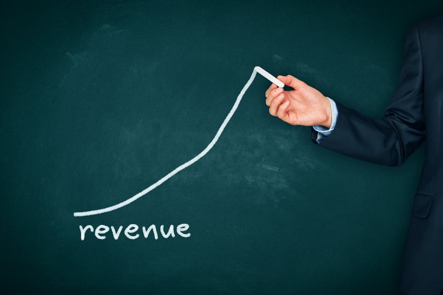 Hand drawing a graph and the word "revenue" on a chalkboard