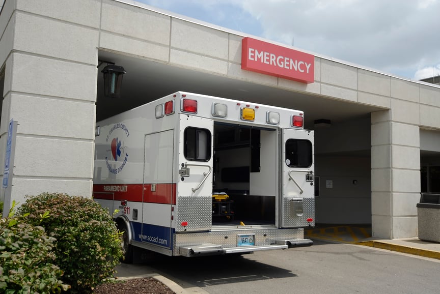 Ambulance parked under an emergency sign