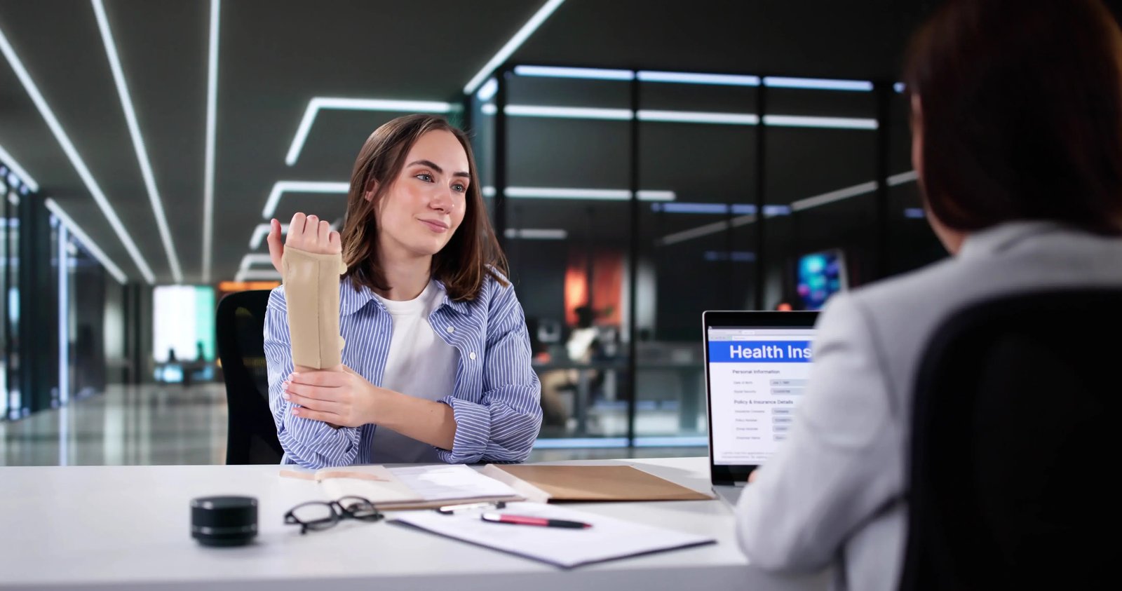A woman with a broken wrist talking to a professional at a desk.