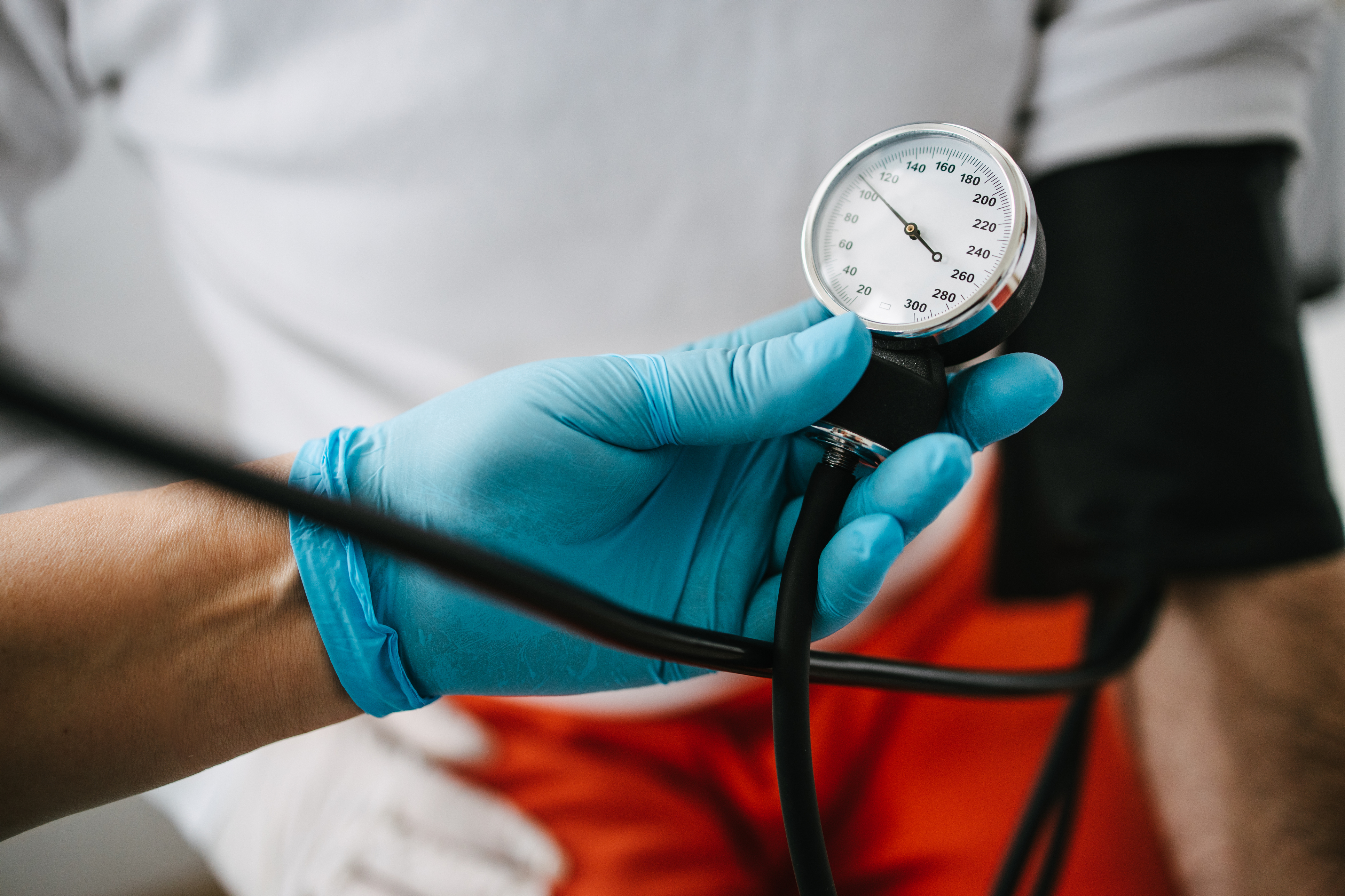 A gloved hand is holding a blood-pressure meter